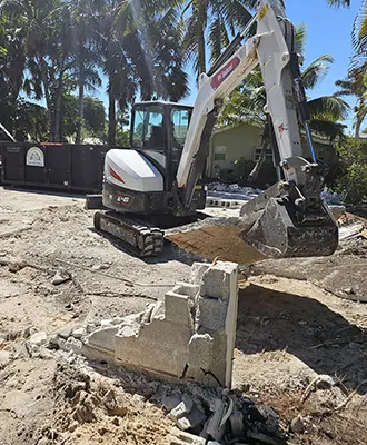 Eco Demolitions backhoe on a job site ripping out the concrete foundation of a building in Southwest Florida.