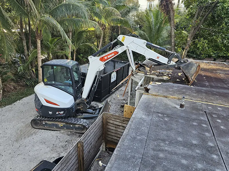 An Eco Demolitions Bobcat backhoe working on a commercial job site in Southwest Florida, removing the roof of a building.