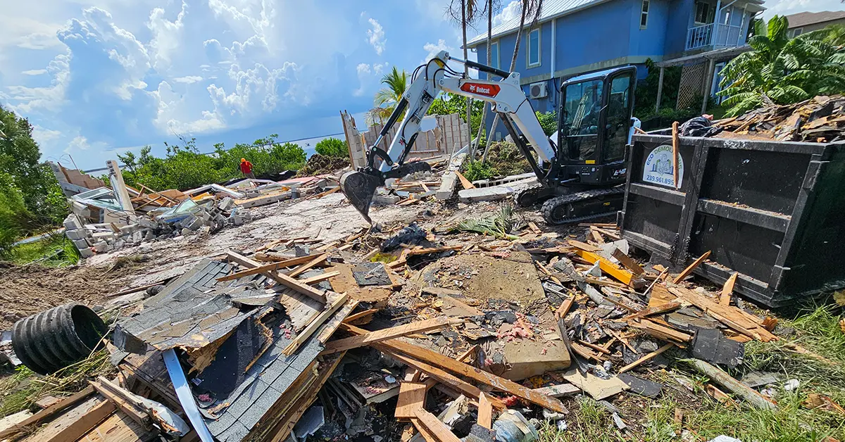 An Eco Demolition backhoe working on a job site, removing deconstruction debris from a Southwest Florida beach residence that has been leveled.
