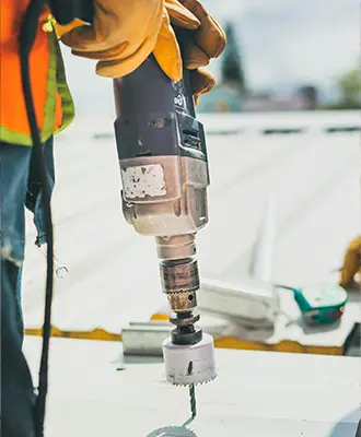 Photo of a construction worker holding a coring drill with a diamond-tipped bit.