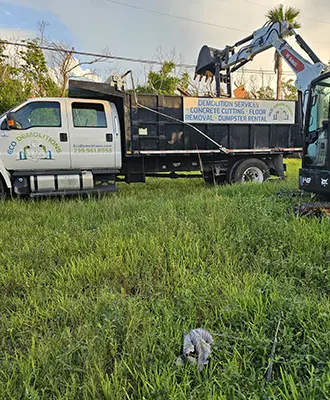 Eco Demolitions dumpster truck on a job site, getting filled with construction debris by a backhoe.