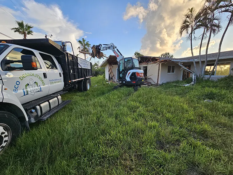 Eco Demolitions Bobcat backhoe and dump truck working on a residential job site in Southwest Florida, removing deconstruction debris from a house.