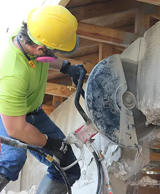 Eco Demolitions employee performing a concrete cutting service on a building.