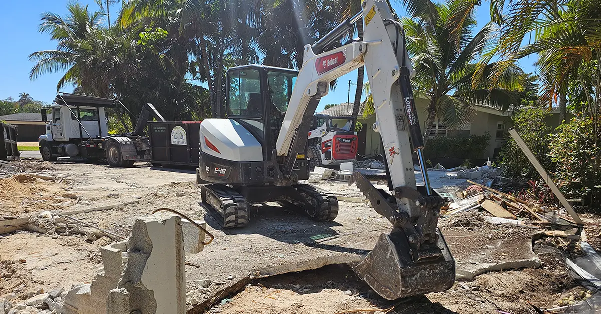 Eco Demolitions Bobcat backhoe pulling up a concrete foundation for disposal at a residential job site.