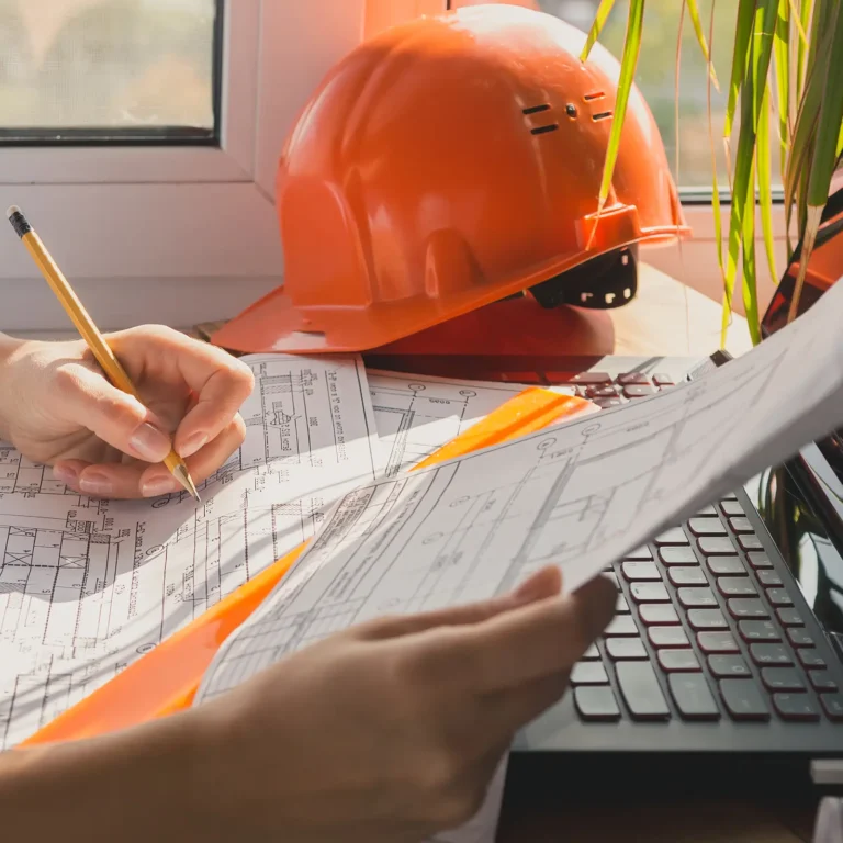 Understanding the Demolition Permit Process in Collier County. Featuring a close-up photo of a business person's hands filling out permit application forms, with a hard hat next to them.