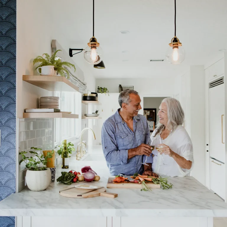 How to Plan a Successful Home Renovation in Naples, FL. Featuring a photo of a mature couple in their modernized kitchen, cooking together.