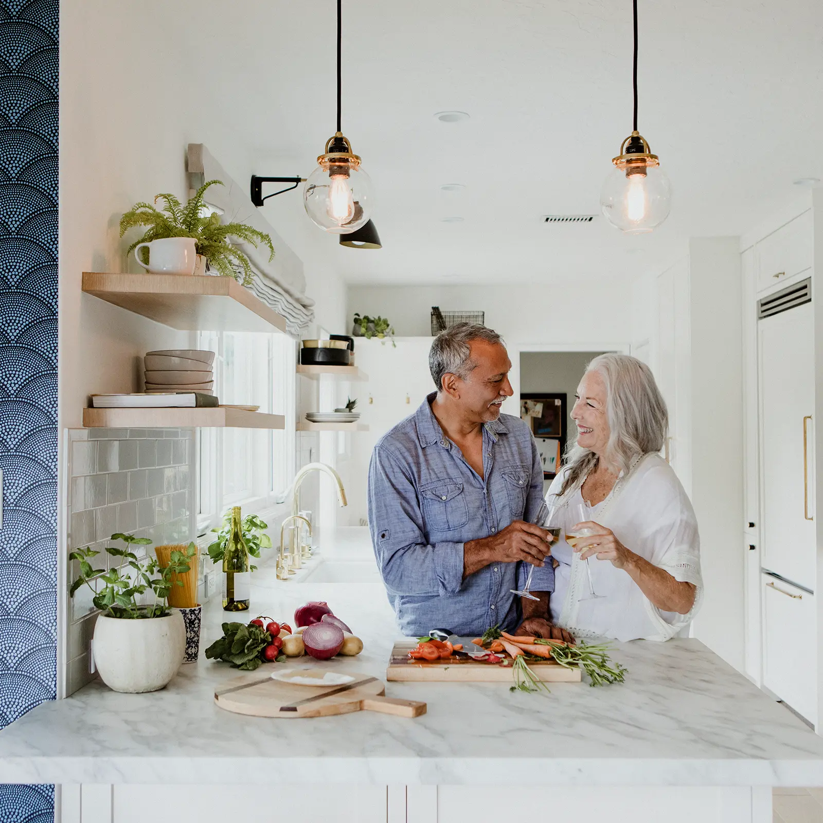 How to Plan a Successful Home Renovation in Naples, FL. Featuring a photo of a mature couple in their modernized kitchen, cooking together.