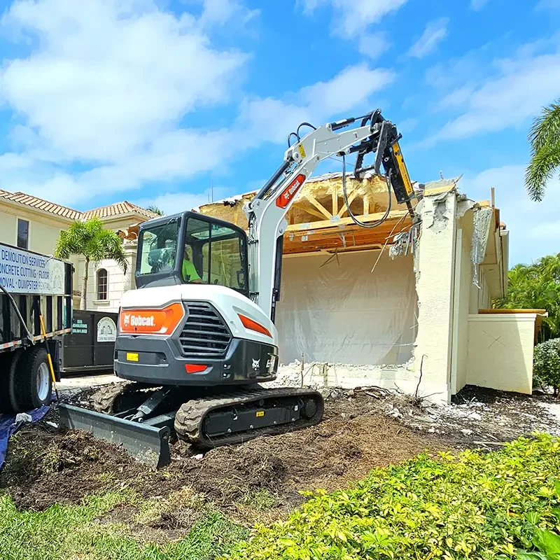 Selective demolition of an exterior wall of a nice house in Southwest Florida to make way for a new addition. The selective demolition is performed by an Eco Demolitions backhoe with a jackhammer attachment, which is delicately breaking down the desired wall while avoiding necessary structures inside.